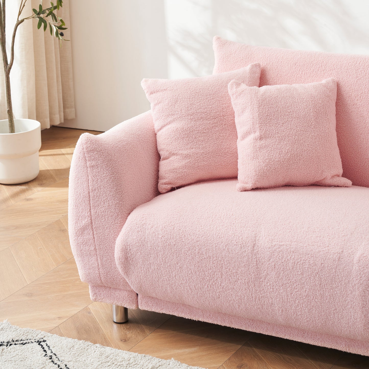 The 86.6 inch teddy fleece pink sofa with four throw pillows and hardware feet can sit comfortably in an apartment bedroom without taking up space